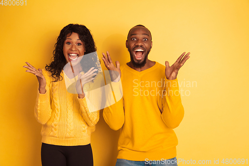 Image of Young emotional african-american man and woman on yellow background