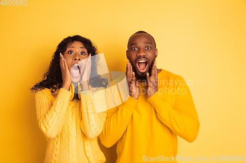 Image of Young emotional african-american man and woman on yellow background