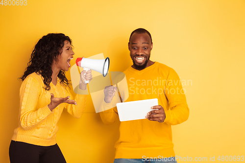 Image of Young emotional african-american man and woman on yellow background