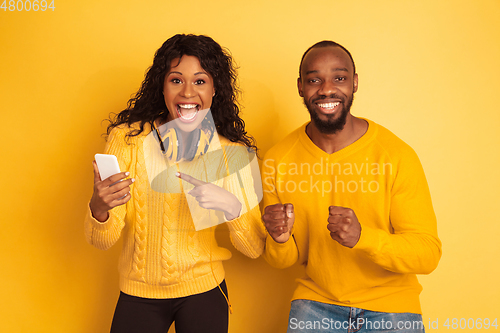 Image of Young emotional african-american man and woman on yellow background