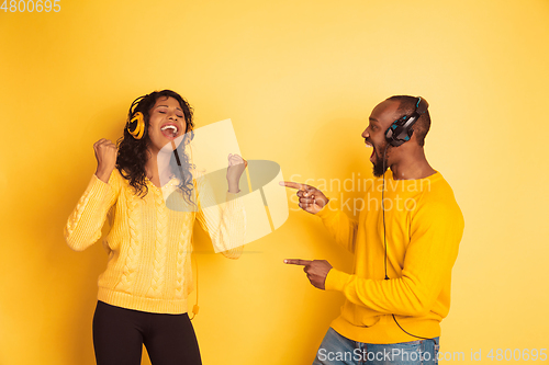 Image of Young emotional african-american man and woman on yellow background