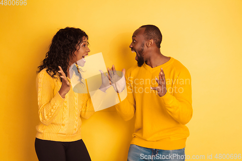 Image of Young emotional african-american man and woman on yellow background