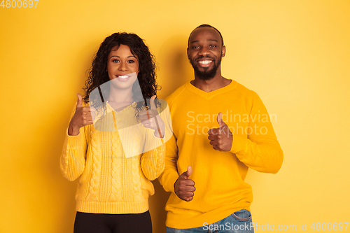 Image of Young emotional african-american man and woman on yellow background