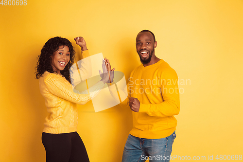 Image of Young emotional african-american man and woman on yellow background