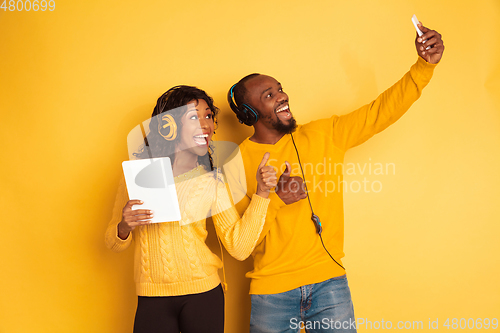 Image of Young emotional african-american man and woman on yellow background