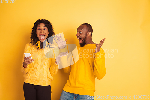 Image of Young emotional african-american man and woman on yellow background