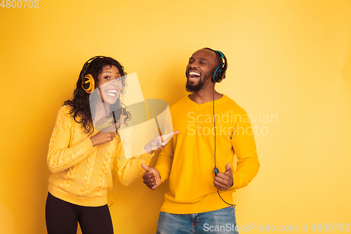 Image of Young emotional african-american man and woman on yellow background