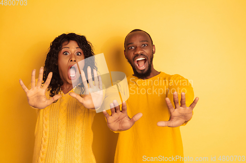 Image of Young emotional african-american man and woman on yellow background