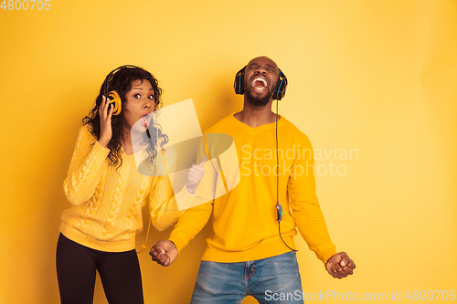 Image of Young emotional african-american man and woman on yellow background