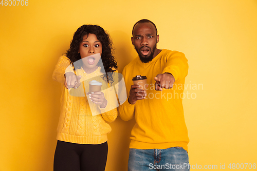 Image of Young emotional african-american man and woman on yellow background