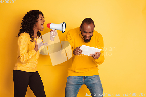 Image of Young emotional african-american man and woman on yellow background