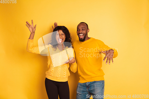 Image of Young emotional african-american man and woman on yellow background