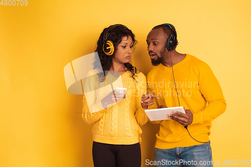 Image of Young emotional african-american man and woman on yellow background