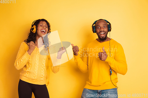 Image of Young emotional african-american man and woman on yellow background