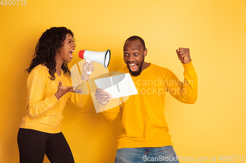 Image of Young emotional african-american man and woman on yellow background