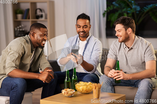 Image of male friends with smartphone drinking beer at home