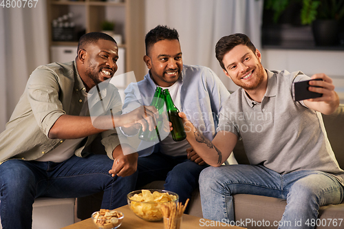 Image of male friends with smartphone taking selfie at home