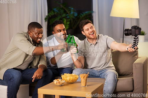 Image of male video blogger with friends and camera at home