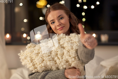 Image of happy young woman with soft pillow in bed at home