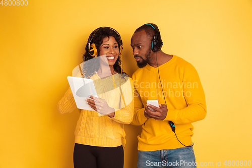 Image of Young emotional african-american man and woman on yellow background