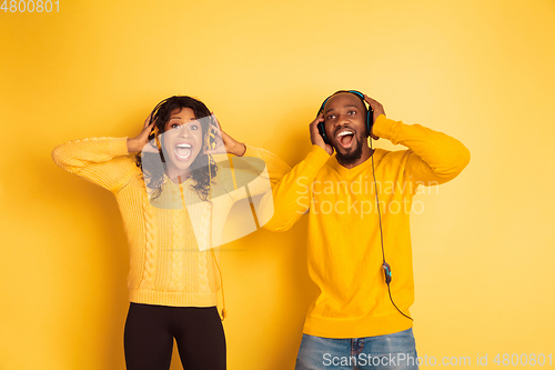 Image of Young emotional african-american man and woman on yellow background