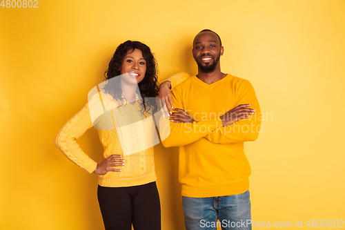 Image of Young emotional african-american man and woman on yellow background
