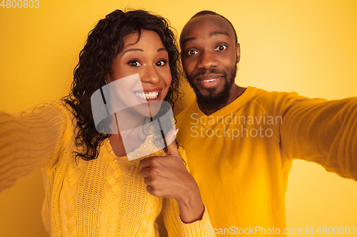 Image of Young emotional african-american man and woman on yellow background