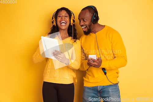 Image of Young emotional african-american man and woman on yellow background