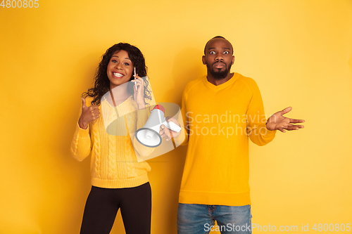 Image of Young emotional african-american man and woman on yellow background