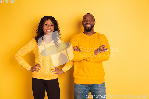 Image of Young emotional african-american man and woman on yellow background
