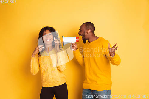 Image of Young emotional african-american man and woman on yellow background