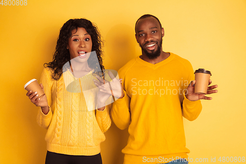 Image of Young emotional african-american man and woman on yellow background