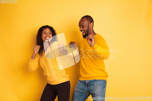 Image of Young emotional african-american man and woman on yellow background