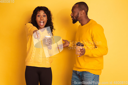 Image of Young emotional african-american man and woman on yellow background