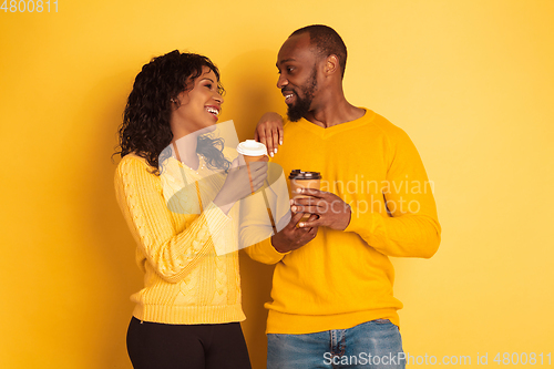 Image of Young emotional african-american man and woman on yellow background