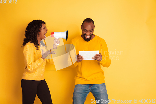 Image of Young emotional african-american man and woman on yellow background