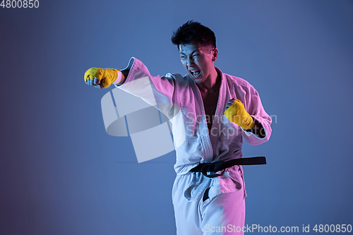 Image of Confident korean man in kimono practicing hand-to-hand combat, martial arts