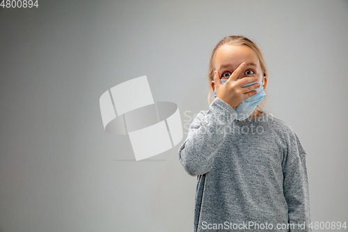 Image of Caucasian girl wearing the respiratory protection mask against air pollution and dusk on grey studio background