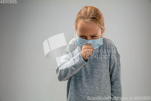 Image of Caucasian girl wearing the respiratory protection mask against air pollution and dusk on grey studio background