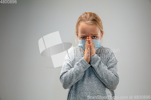 Image of Caucasian girl wearing the respiratory protection mask against air pollution and dusk on grey studio background