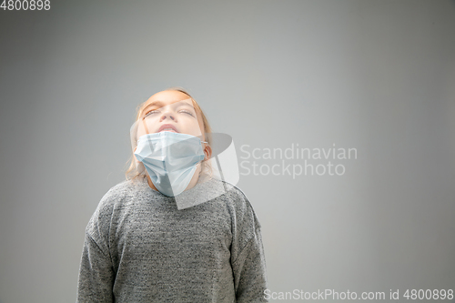Image of Caucasian girl wearing the respiratory protection mask against air pollution and dusk on grey studio background