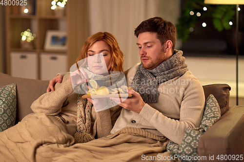 Image of sick young couple drinking tea with lemon at home