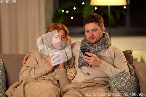 Image of sick young couple with smartphone at home