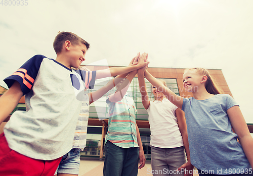 Image of group of children making high five at school yard