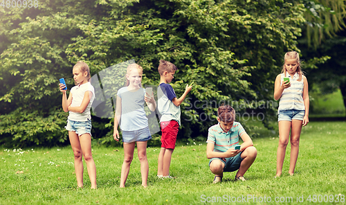 Image of kids with smartphones playing game in summer park