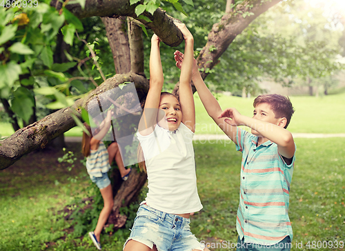 Image of happy kids hanging on tree in summer park