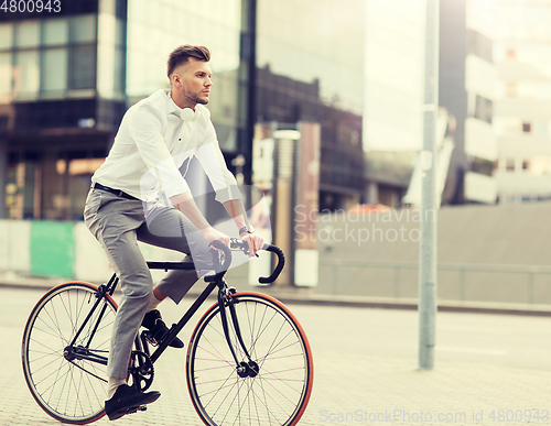 Image of man with headphones riding bicycle on city street