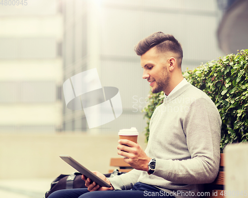 Image of man with tablet pc and coffee on city street bench