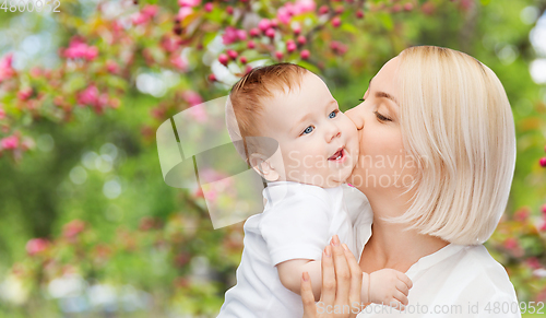 Image of close up of happy mother kissing baby over garden