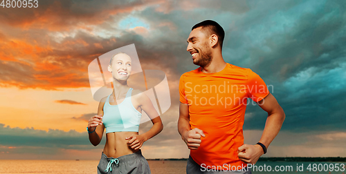 Image of smiling couple running over sea